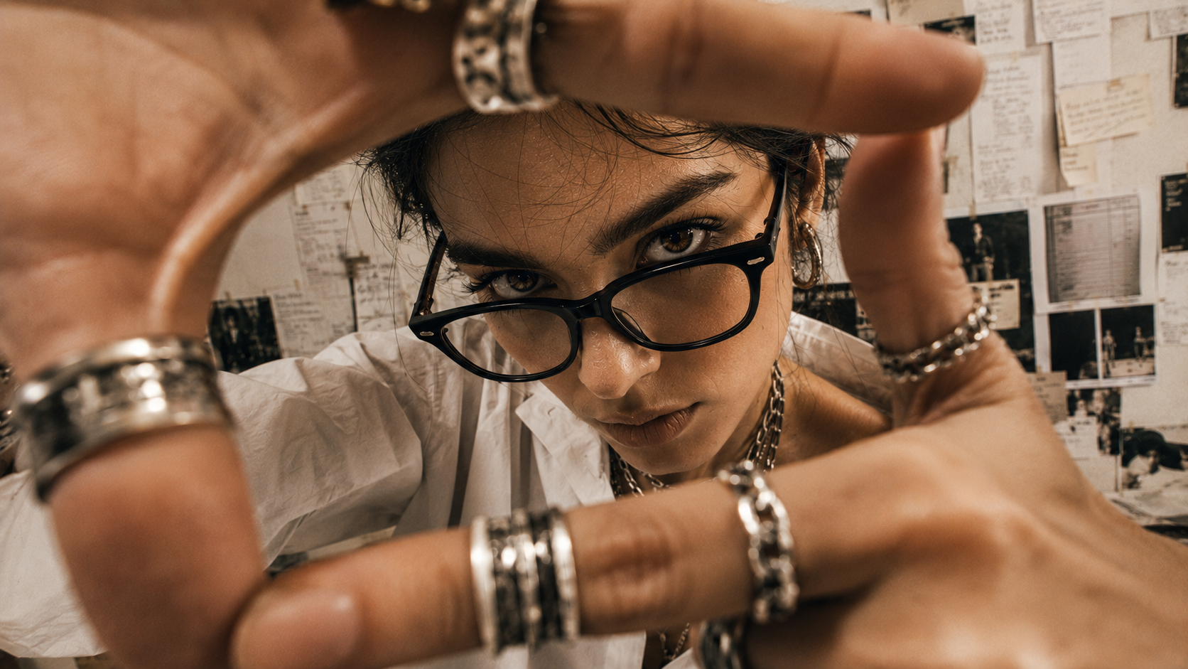 AI-directed fashion portrait — model framing the lens with ringed hands against an archive wall